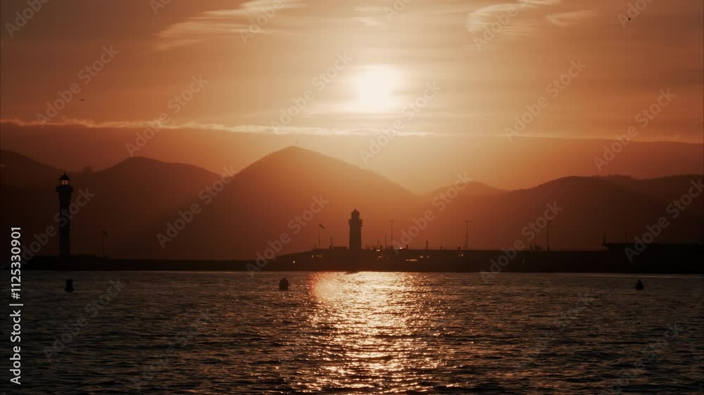Distant view of a lighthouse with the mountains on the background at sunset Distant view of a lighthouse with the mountains on the background at sunset