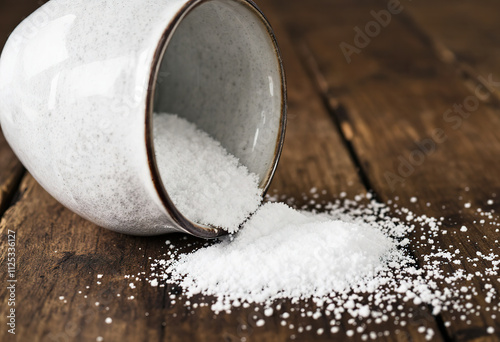 a ceramic bowl tipped over on a wooden surface, spilling its contents bath salt
