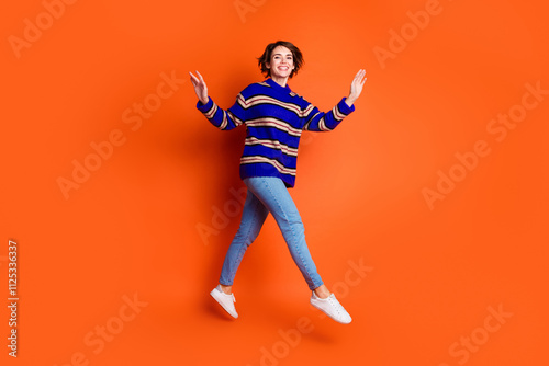 Full body length photo of jumping trampoline funky model millennial woman trendy outfit isolated on orange color background