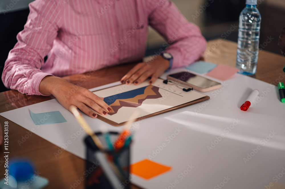 Businesswoman analyzing statistical charts on clipboard during meeting