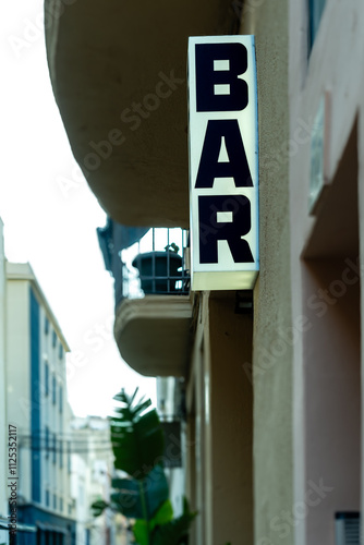 Illuminated bar sign on a narrow urban street, highlighting the vibrant nightlife and architectural charm of the area photo