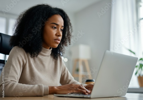 Young businesswoman concentrating on her laptop, working in a bright and modern office space