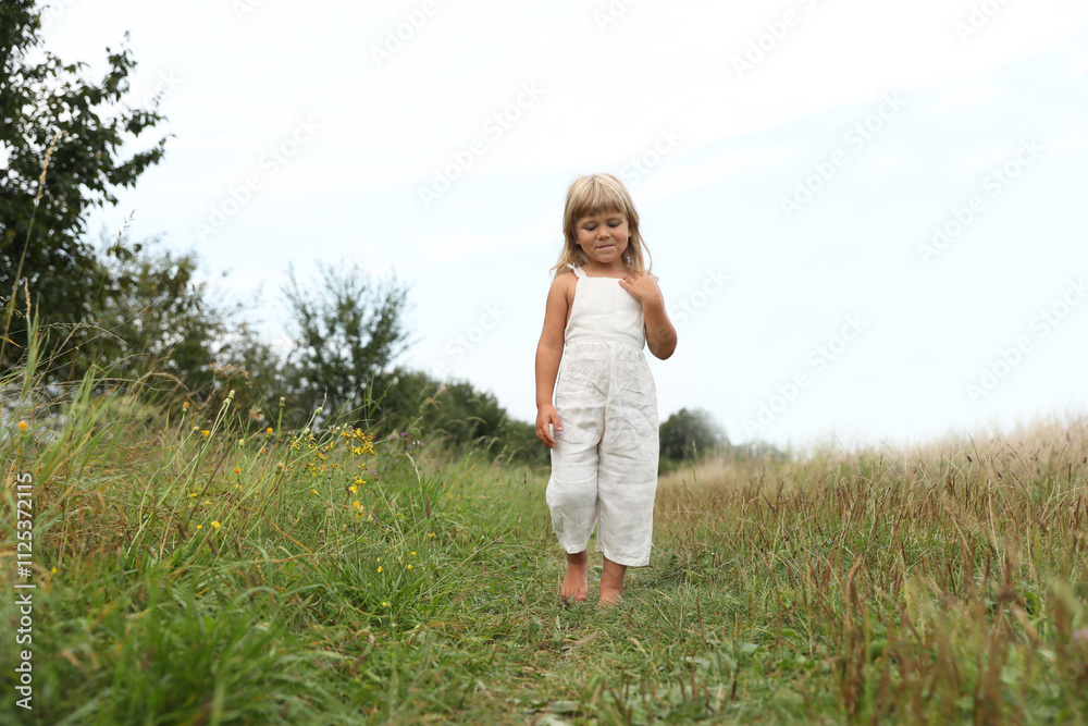 Cute little girl walking barefoot at meadow. Child enjoying beautiful nature Cute little girl walking barefoot at meadow. Child enjoying beautiful nature
