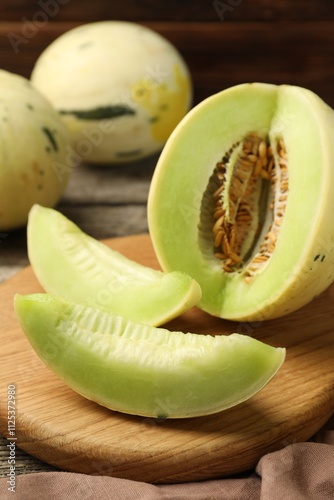 Fresh whole and cut honeydew melons on wooden table, closeup