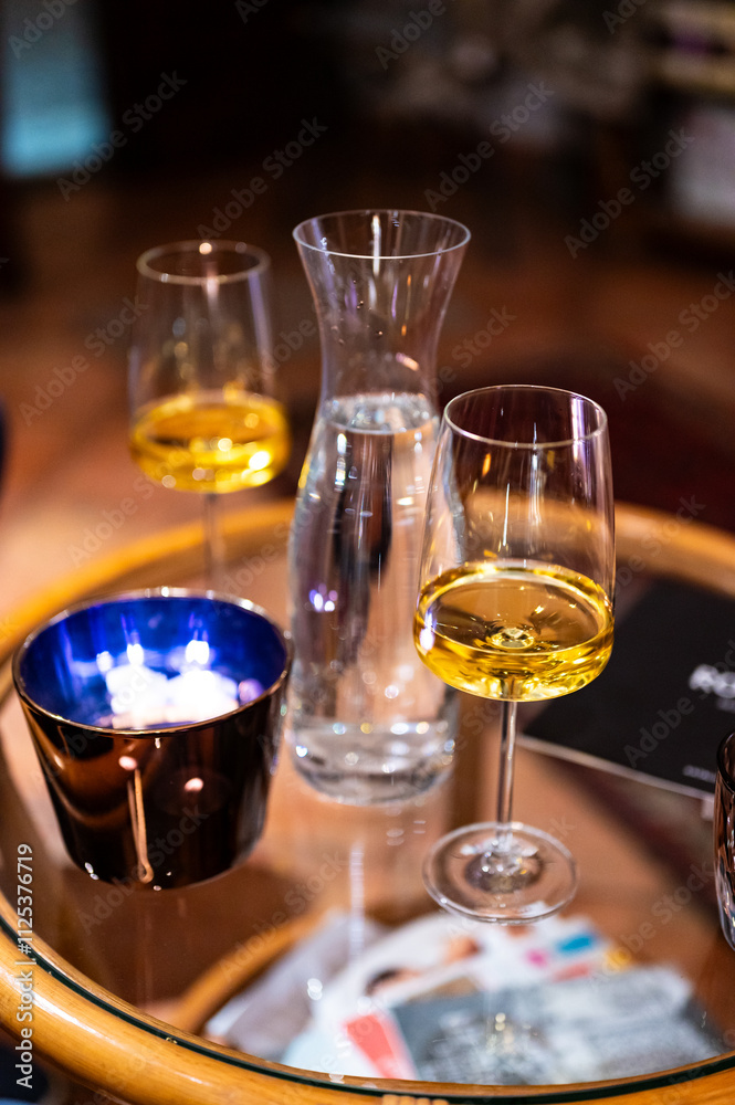 A close-up shot of a table with a modern wine glass filled with white wine, capturing the elegance of the glass and the refined atmosphere of the setting