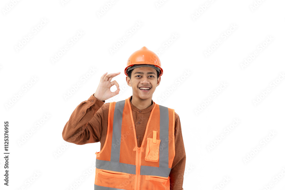 Young Indonesian male construction worker in full safety gear doing ok gesture while looking at camera, industrial and construction concept, isolated on white background.
