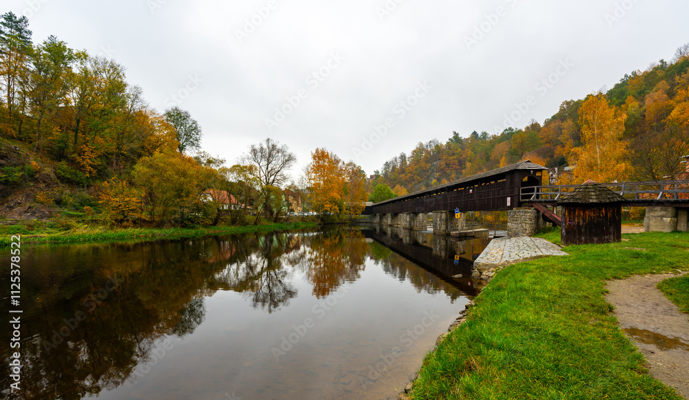 A scenic view of a wooden footbridge over the Vltava River in Cesky Krumlov, near Nove Spoli, surrounded by nature and offering a tranquil atmosphere in the heart of the landscape