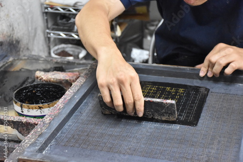 Photography The intricate printing of a Japanese Inden pattern, as lacquer urushi is delicately applied onto soft deer leather, forming shimmering, textured designs under skilled hands
