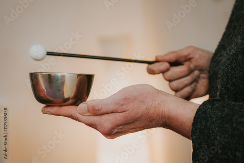 Hand hält kleine Klangschale und Filzschlägel, Holzschlägel