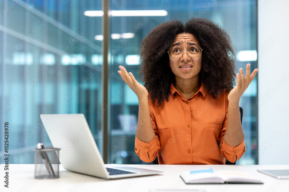 A frustrated office worker with hands raised in confusion, sitting at her desk with a laptop. The image captures a common workplace scenario of stress and uncertainty. A frustrated office worker with hands raised in confusion, sitting at her desk with a laptop. The image captures a common workplace scenario of stress and uncertainty.