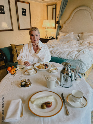 A woman enjoying a leisurely breakfast in a lavish hotel room