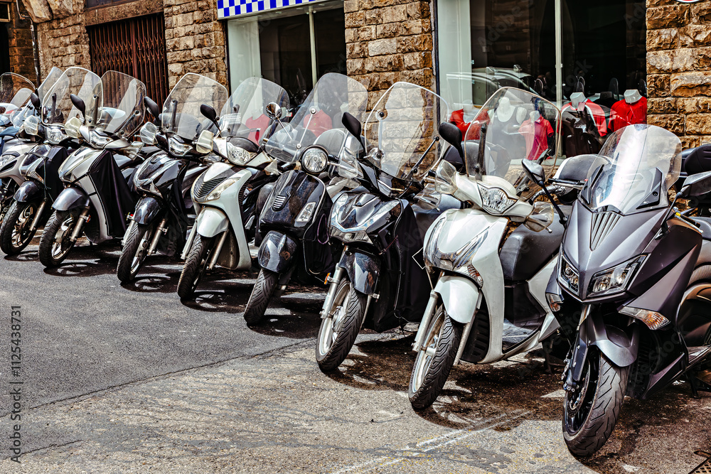 Motorcycles parked along a historic street in central medieval Florence amid ancient stone architecture