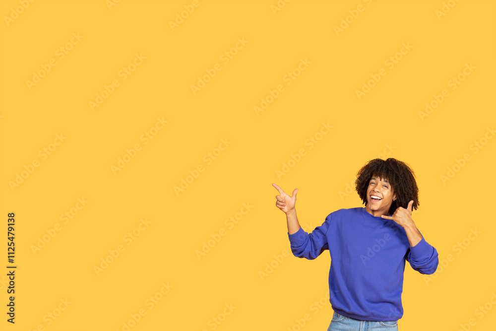A cheerful young man poses energetically against a bright yellow backdrop. His relaxed style reflects a modern lifestyle, showcasing confidence and joy in the moment, copy space A cheerful young man poses energetically against a bright yellow backdrop. His relaxed style reflects a modern lifestyle, showcasing confidence and joy in the moment, copy space