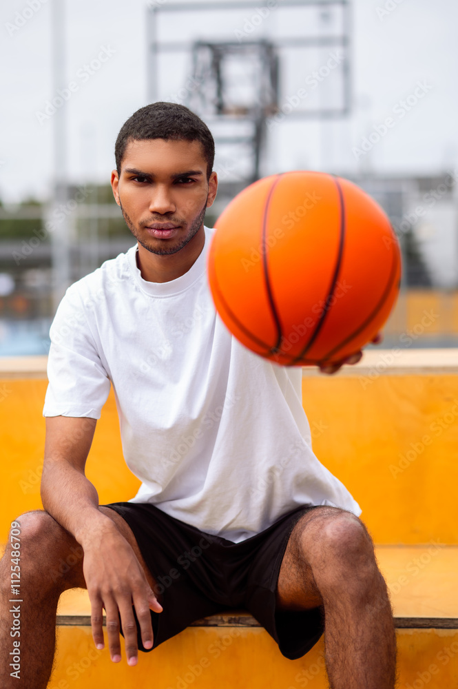 Handsome young basketball player with a ball in hands