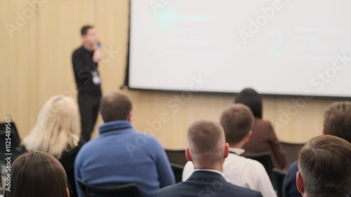 Speaker engages audience during technology conference presentation. Participants focused on learning new industry trends.