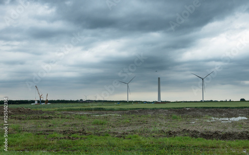 Cloudy day at a wind farm construction site.  Muddy ground, cranes, and wind turbines. photo