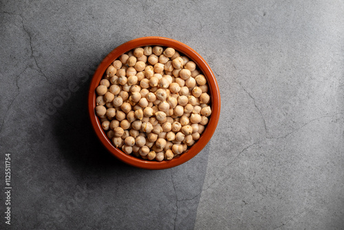 Earthenware bowl full of chickpeas on a kitchen worktop in a zenithal photograph
 photo