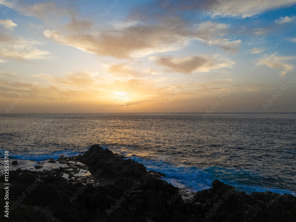 Atlantic ocean sunset in Tenerife with soft golden hues illuminating the horizon, waves gently crashing against the rocky shore. A scene that evokes a sense of tranquility and connection with nature Atlantic ocean sunset in Tenerife with soft golden hues illuminating the horizon, waves gently crashing against the rocky shore. A scene that evokes a sense of tranquility and connection with nature