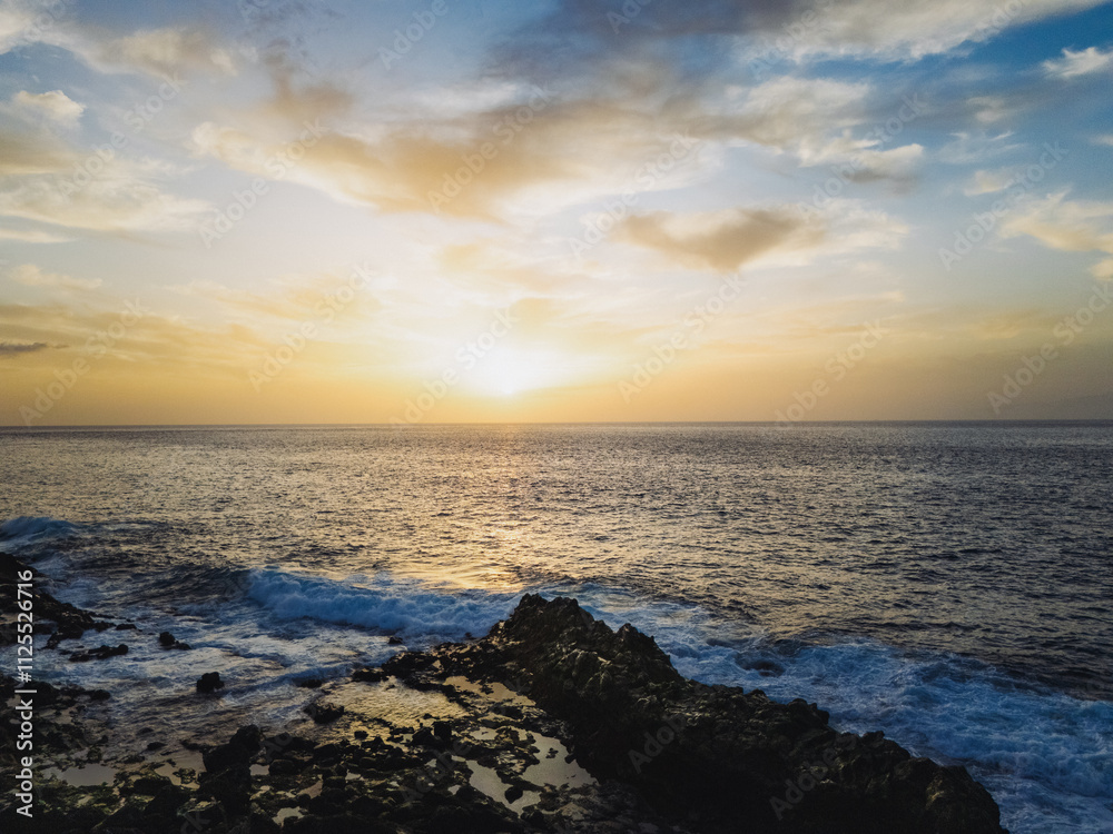 Atlantic ocean sunset in Tenerife with soft golden hues illuminating the horizon, waves gently crashing against the rocky shore. A scene that evokes a sense of tranquility and connection with nature Atlantic ocean sunset in Tenerife with soft golden hues illuminating the horizon, waves gently crashing against the rocky shore. A scene that evokes a sense of tranquility and connection with nature