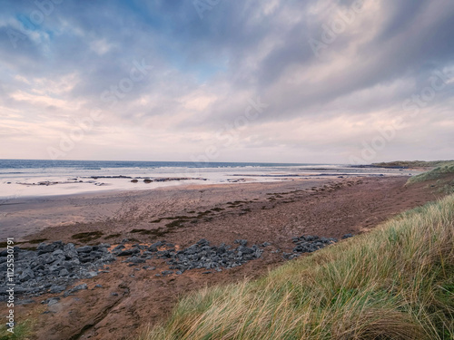 Stunning Fanore beach in county Clare, Ireland. Popular travel and tourist hotspot with amazing Irish nature scenery view. Sandy beach with rocks, powerful ocean with waves and dramatic sky. photo