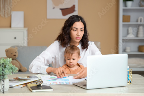 Cute little baby and young mother working with laptop on maternity leave at home