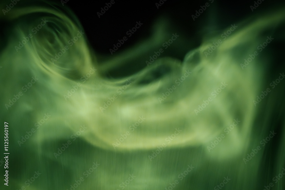 Obraz premium Abstract image of flowing green smoke patterns against a dark background, evoking a calm and mystical atmosphere with subtle motion and texture.