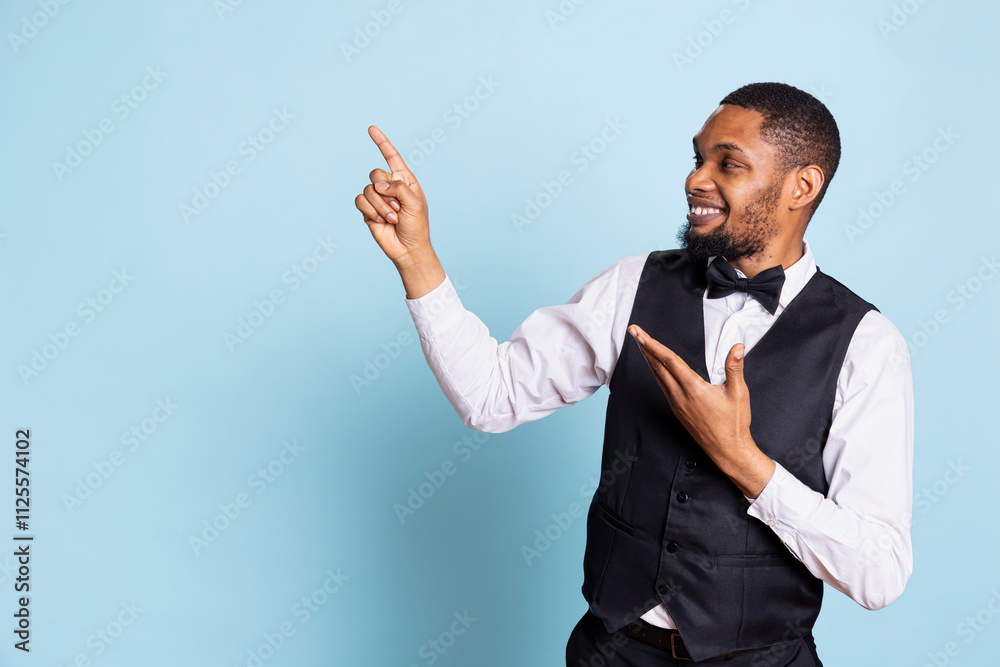 Hotel concierge pointing at something to the left or right on camera, indicating the direction for facilities at the five star lodging. Doorkeeper wearing a tuxedo at his job. Hotel concierge pointing at something to the left or right on camera, indicating the direction for facilities at the five star lodging. Doorkeeper wearing a tuxedo at his job.
