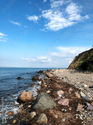 Rocky Shoreline With Bright Blue Sky and Calm Waves