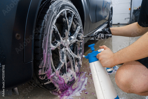 Professional car wash. Close up view of car wheel being washed with the brush and soap