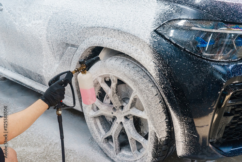 Applying foam to a car at a car wash. Spraying foam onto a car with a spray bottle. Detergent