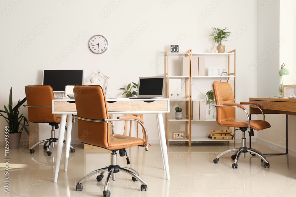 Interior of light office with desks, shelf unit and plants Interior of light office with desks, shelf unit and plants