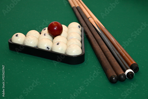 Balls collected in triangles and cues on a green background of a billiard table photo