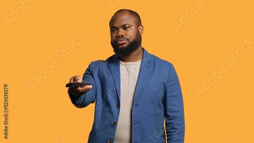 Man zapping through channels, watching news broadcast, isolated over studio background. African american person using remote control to select television station to enjoy, camera A photo