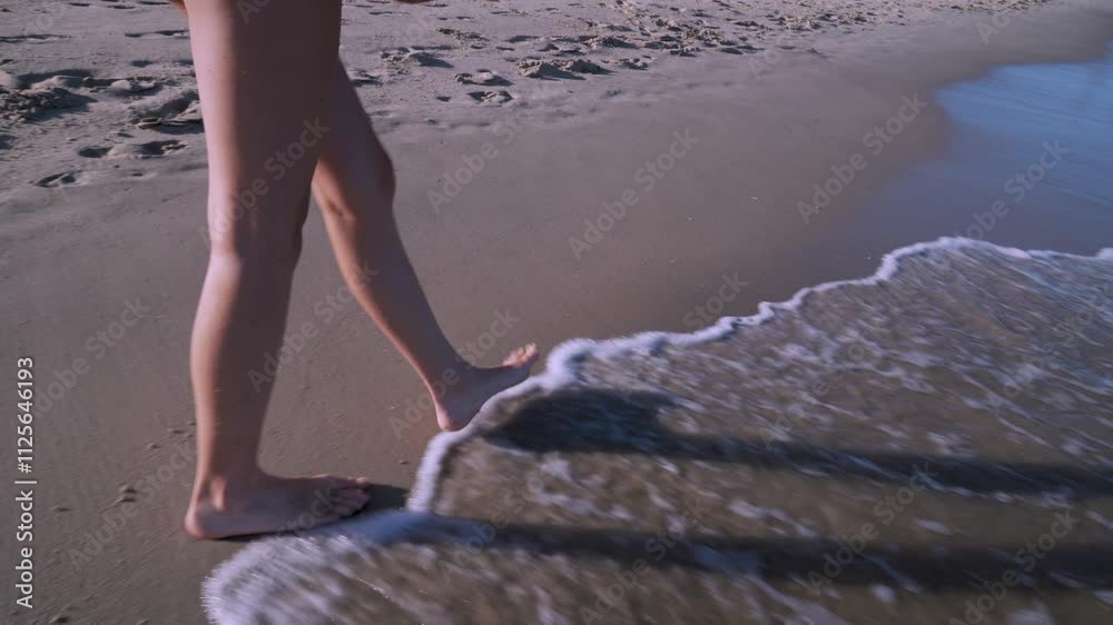 Piernas de chica joven paseando por la orilla del mar en la playa un día sensacional de vacaciones en verano.