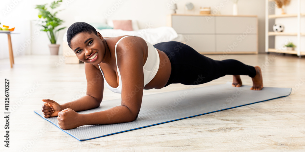 Sports and weight loss concept. Overweight African American woman doing exercises on mat at home, full length. Plus size black lady standing in elbow plank, strengthening her body muscles Sports and weight loss concept. Overweight African American woman doing exercises on mat at home, full length. Plus size black lady standing in elbow plank, strengthening her body muscles