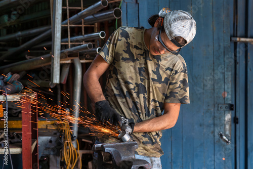 A skilled craftsman meticulously grinds metal in a workshop, focused and surrounded by tools photo