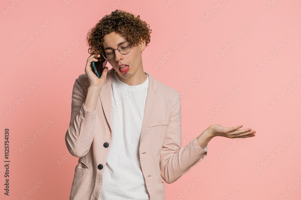 Disinterested man with curly hair having annoyed boring talk on smartphone. Guy tired sleepy freelancer talking on mobile phone with friend, making online conversation isolated on pink background Disinterested man with curly hair having annoyed boring talk on smartphone. Guy tired sleepy freelancer talking on mobile phone with friend, making online conversation isolated on pink background