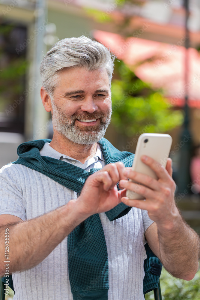 Handsome mature man using smartphone typing text messages tired looking up thinking and browsing internet social media web app working chatting online outdoor. Guy in urban city street. Lifestyles.