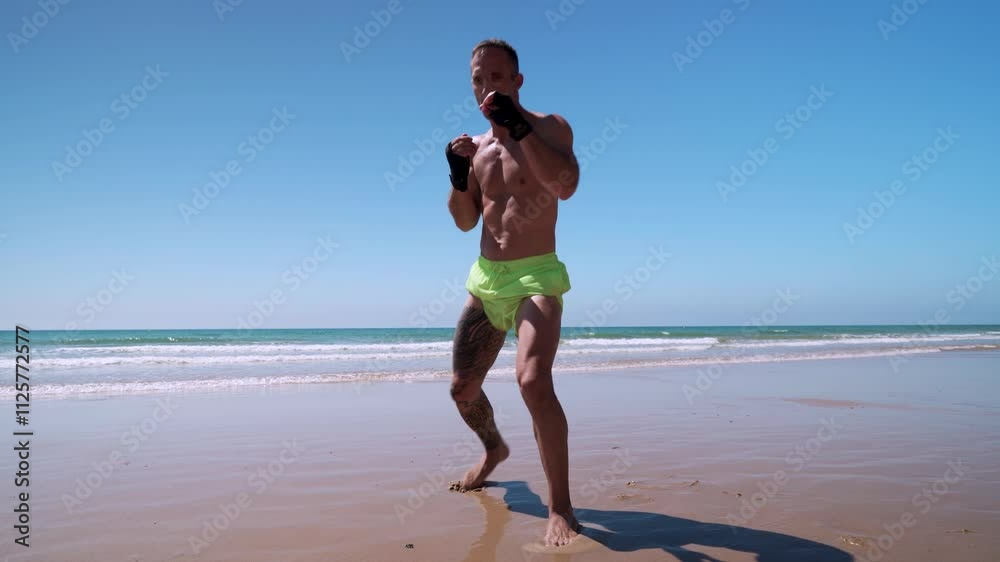 Hombre realizando ejercicios de artes marciales como kick boxing o boxeo en la playa y al fina ataca a la cámara con una patada voladora.