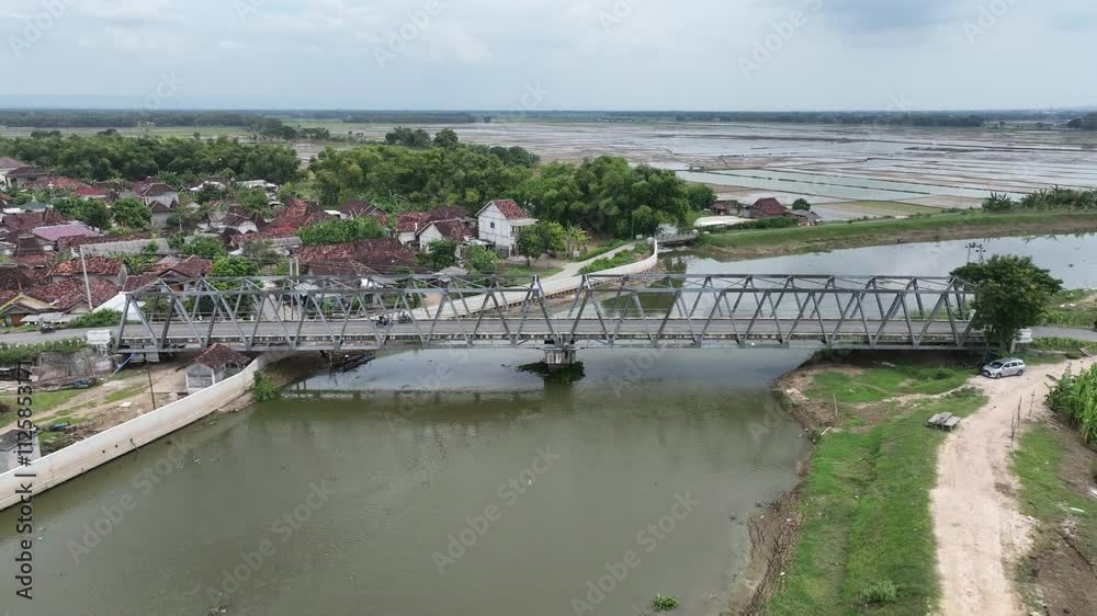 Drone video of two spans steel truss bridge type b50 over a river surrounded by rice fields in Sampang, Central Java Indonesia Drone video of two spans steel truss bridge type b50 over a river surrounded by rice fields in Sampang, Central Java Indonesia
