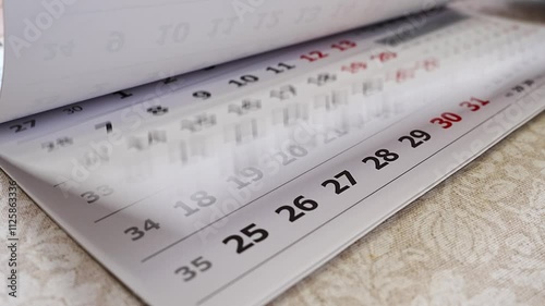 hand is turning the pages of a tear-off wall calendar. Printing calendars with photos as a gift. the rapidity of the passage of time. anticipation of a holiday, event or meeting.