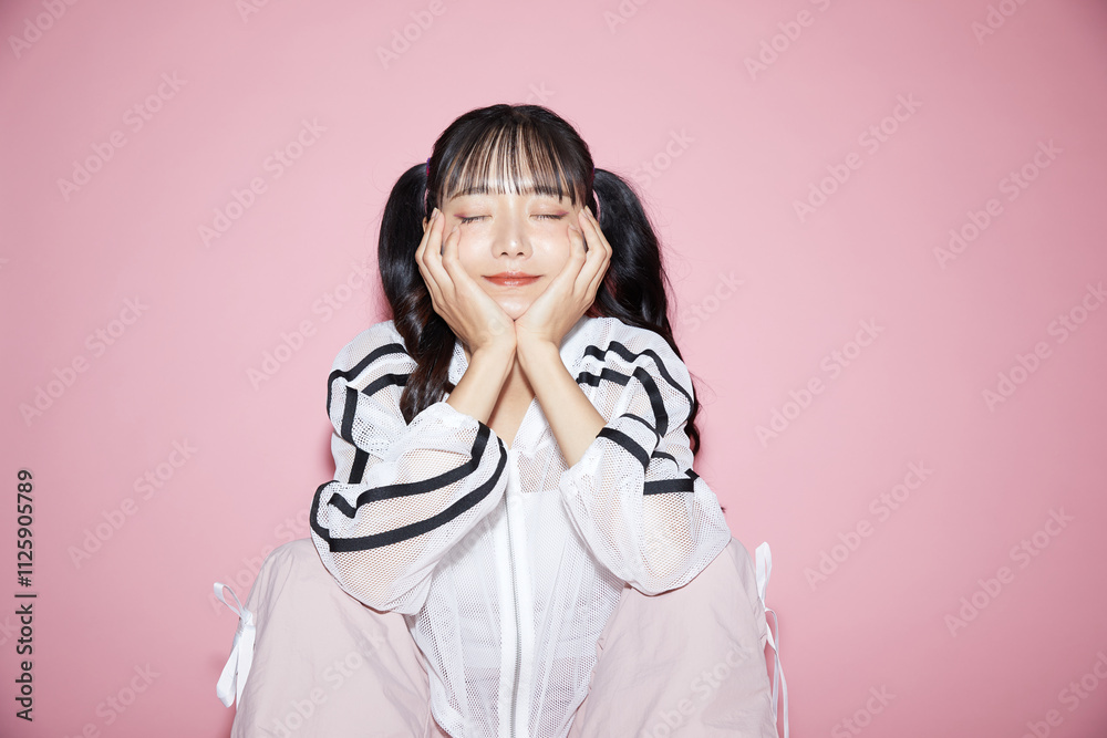 ピンク背景で撮影をしたスポーティな服装をした若い女性のキュートなポートレート