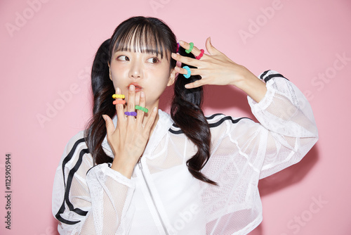 ピンク背景で撮影をしたスポーティな服装をした若い女性のキュートなポートレート