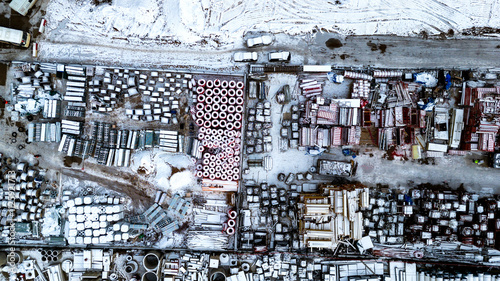 Huge open warehouse of building materials in winter for large trading organization, top view. Various building materials are laid out on street on site. photo