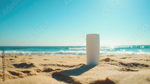 A blank white tube of sunscreen on a sandy beach, with a bright blue sky and clear sunny day in the background.