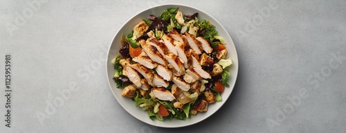 Grilled chicken salad with mixed greens, croutons, and vegetables on a white plate. photo