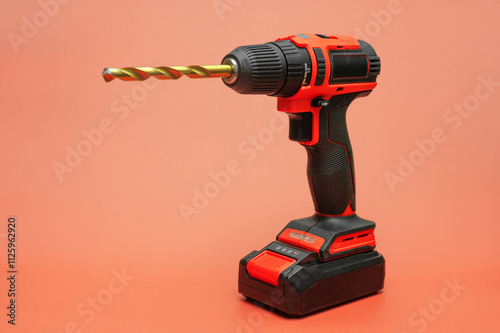 electric cordless screwdriver with a metal drill on a red. isolate