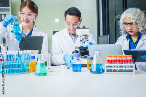 Two Asian men and women sit at a table in a laboratory, conducting research on liquids. They use microscopes, petri dishes, and test tubes filled with various chemicals for analysis