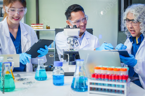 Two Asian men and women sit at a table in a laboratory, conducting research on liquids. They use microscopes, petri dishes, and test tubes filled with various chemicals for analysis