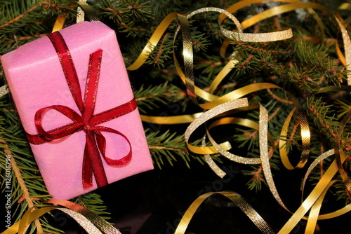 Christmas background with green spruce, gift and candy on a black background